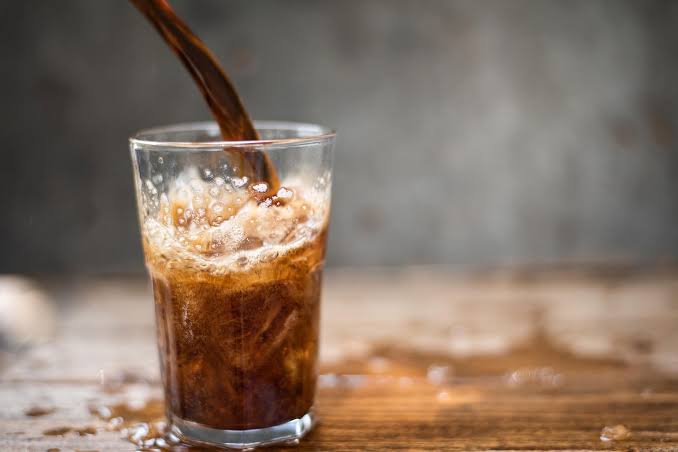 Cola pouring into a glass with ice